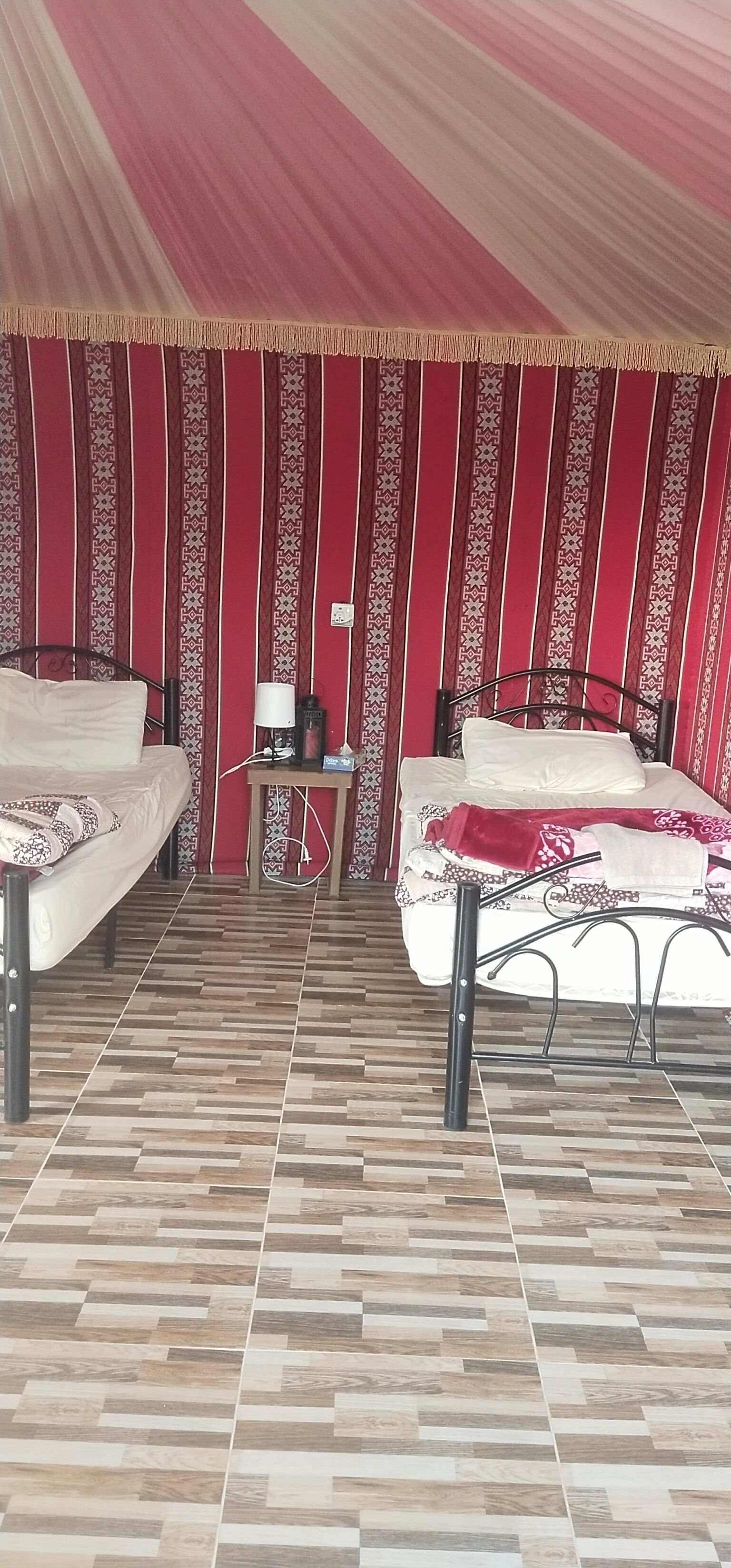 Habitació amb dos llits, una tauleta de nit i una cortina amb dibuixos.
