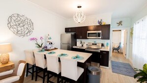 A modern kitchen with dark cabinets, a microwave, and a dining area with a table and chairs. - The Sandy Beach House in Historic Key West (Key West)