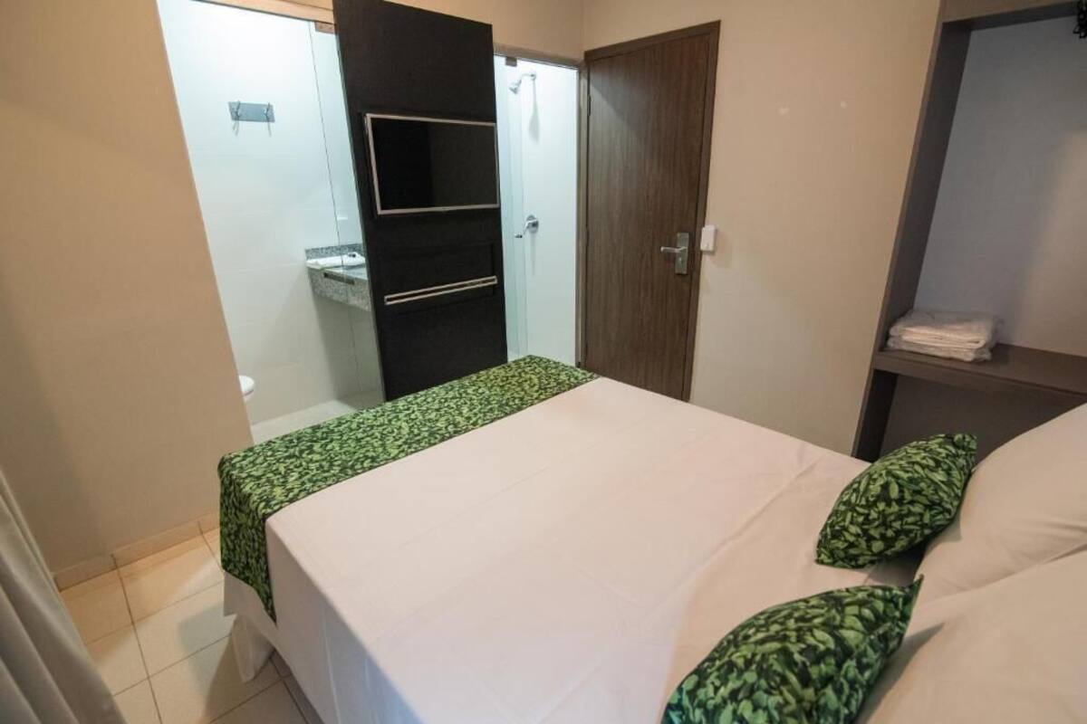 A bedroom with a bed, a wardrobe, and a bathroom visible through an open door.