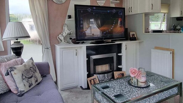 A cozy living room with a television, sofa, and a glass coffee table. - Caravan - Sleeps 8, pet Friendly (Welshpool)