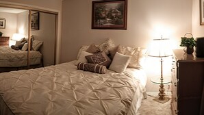 Ein Schlafzimmer mit einem großen Bett, einem Nachttisch mit Lampe, einem Schminktisch und einem Spiegel.