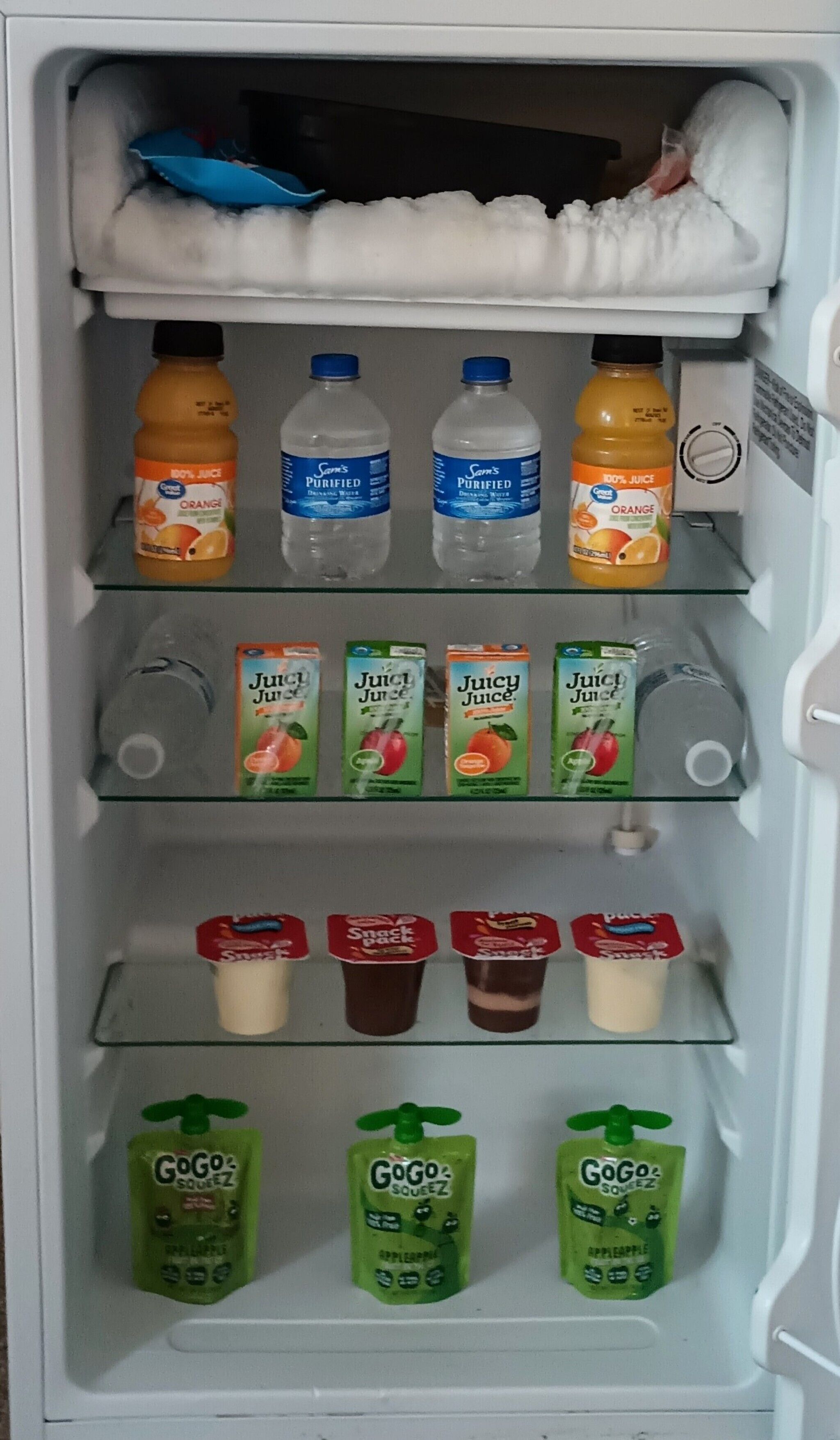 Un refrigerador lleno de diversas bebidas, como jugo, agua y aperitivos.