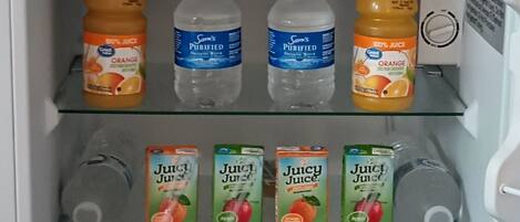 Un refrigerador lleno de diversas bebidas, como jugo, agua y aperitivos.