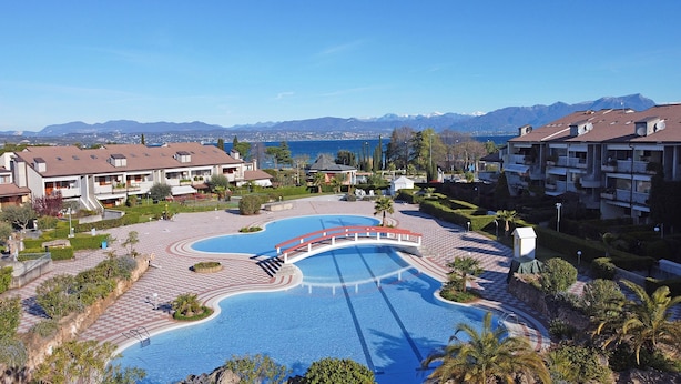 Un resort con piscina central, jardines ajardinados y vistas a la montaña.