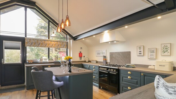 Une cuisine moderne dotée d’un îlot central, de tabourets de bar, d’une cuisinière et d’une grande fenêtre.