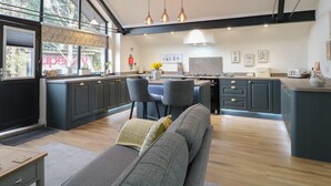 Une cuisine moderne avec des meubles de couleur sombre, un îlot central et des luminaires suspendus.