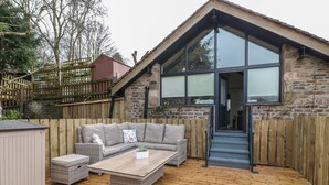 Un espace extérieur accueillant, avec une terrasse en bois, un canapé en osier et une table basse.