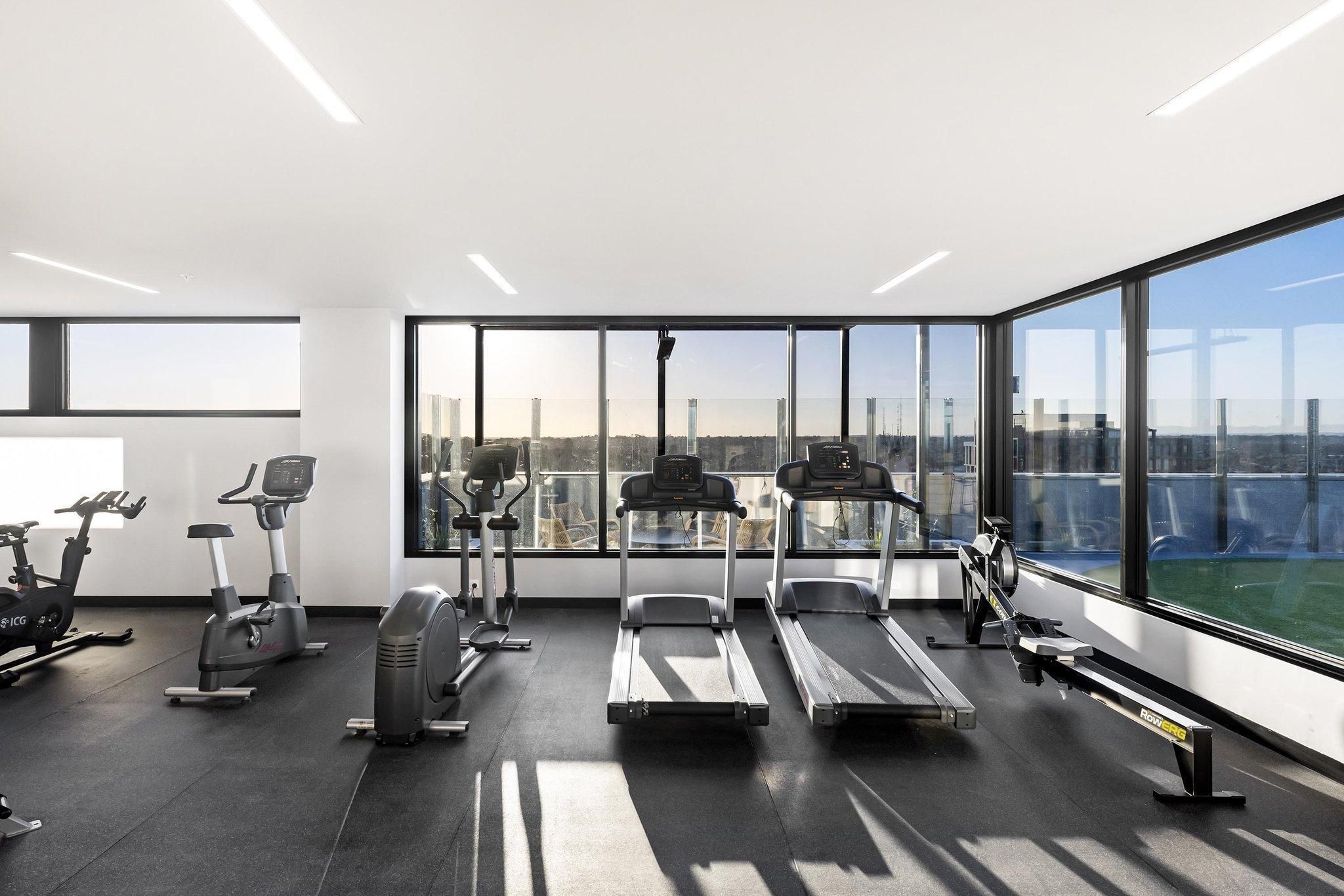 A modern gym with treadmills, stationary bikes, and elliptical machines.