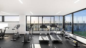 A modern gym with treadmills, stationary bikes, and elliptical machines.
