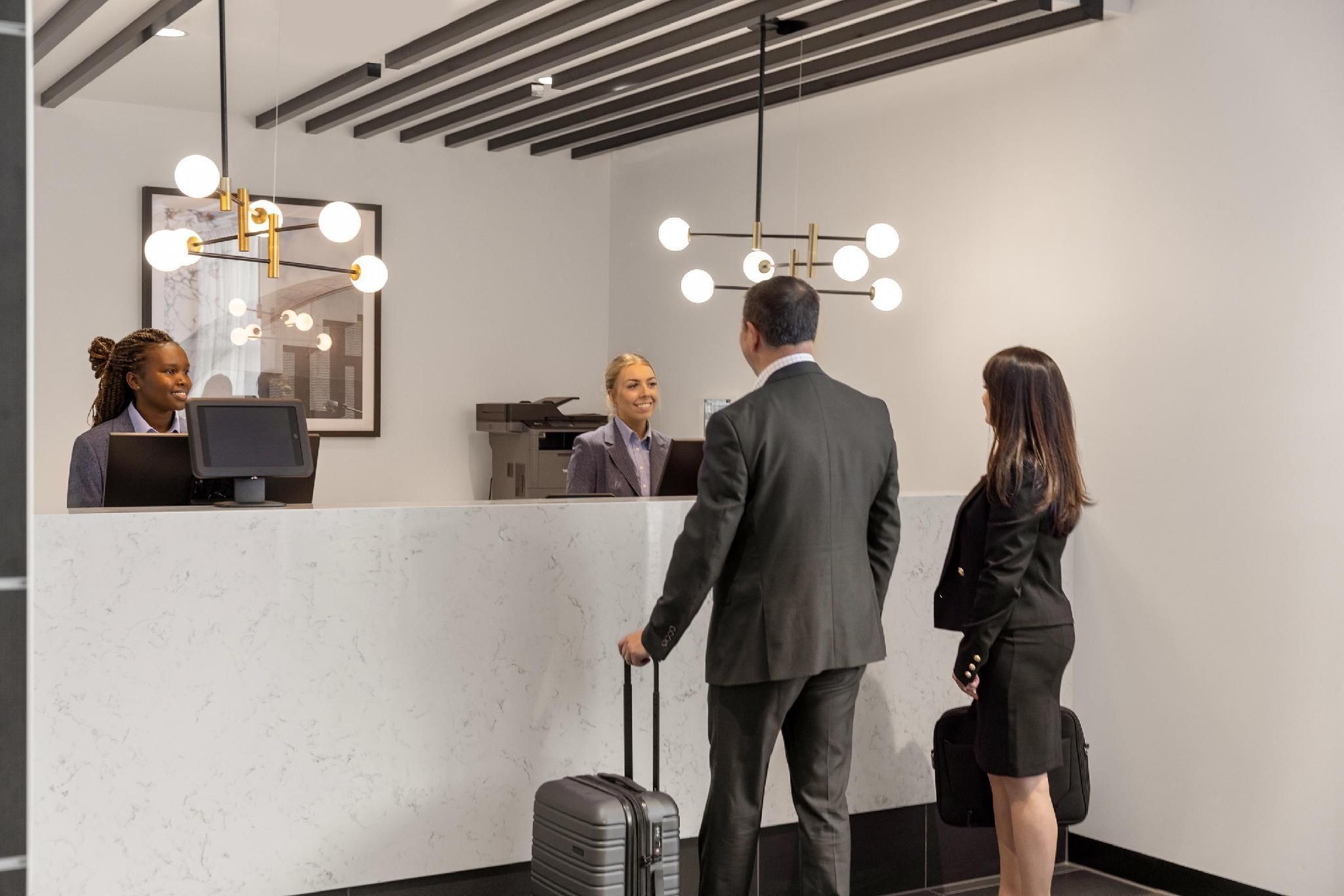 A reception desk with a marble countertop, a modern chandelier, and a framed picture on the wall.