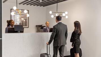 A reception desk with a marble countertop, a modern chandelier, and a framed picture on the wall.
