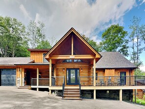 A log cabin with a front porch, a garage, and a stone foundation.