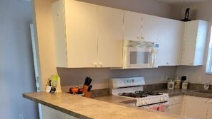 A kitchen with a central island, white cabinets, a microwave, and a stove.