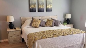 A bedroom with a bed, nightstands, a ceiling fan, and artwork on the wall.