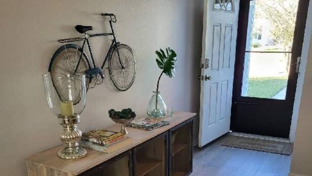 A hallway with a wooden console table, a bicycle, and a door leading outside.