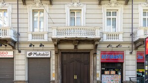 Eine Gebäudefassade mit heruntergelassenen Rollläden, einem Schild für das Café 'Mokabar' und einem Schild mit der Aufschrift 'RISTORANTE' und einer Speisekarte.