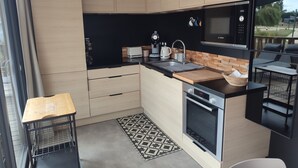 Una cocina moderna con armarios de madera, protector contra salpicaduras negro, un microondas Bosch y un lavamanos.