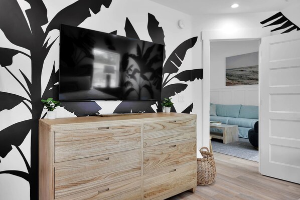 Una sala de estar moderna con un televisor de pantalla plana grande montado sobre un mueble de madera, un sofá azul claro y una puerta blanca.