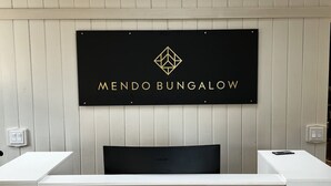 A reception desk with a sign reading "MENDO BUNGALOW" and a Samsung TV. - Mendo Bungalow (Mendocino)
