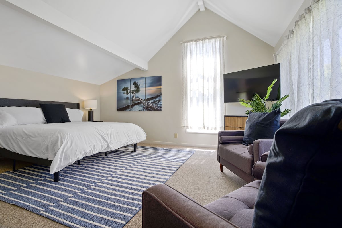 Quarto com cama, sofá, televisão e quadro na parede.