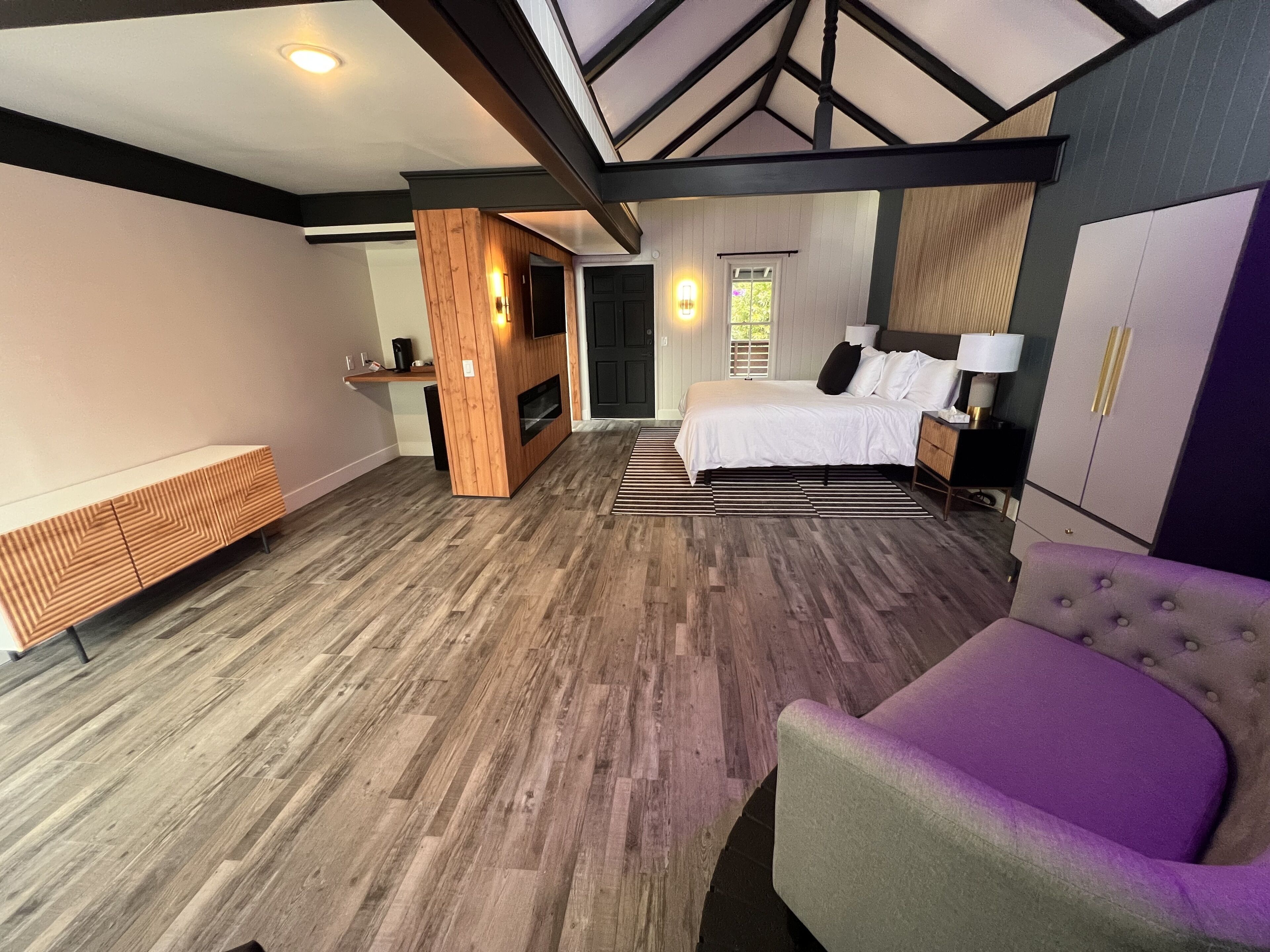 A modern bedroom with a large bed, a built-in TV, and a wooden accent wall.