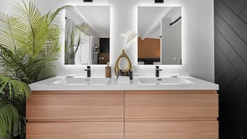Ein modernes Badezimmer mit einem Doppelwaschbecken, Holzschränken und einem großen Spiegel.