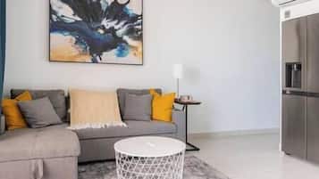 Una sala de estar moderna con un sofá gris, una mesa de centro blanca y un cuadro en la pared.