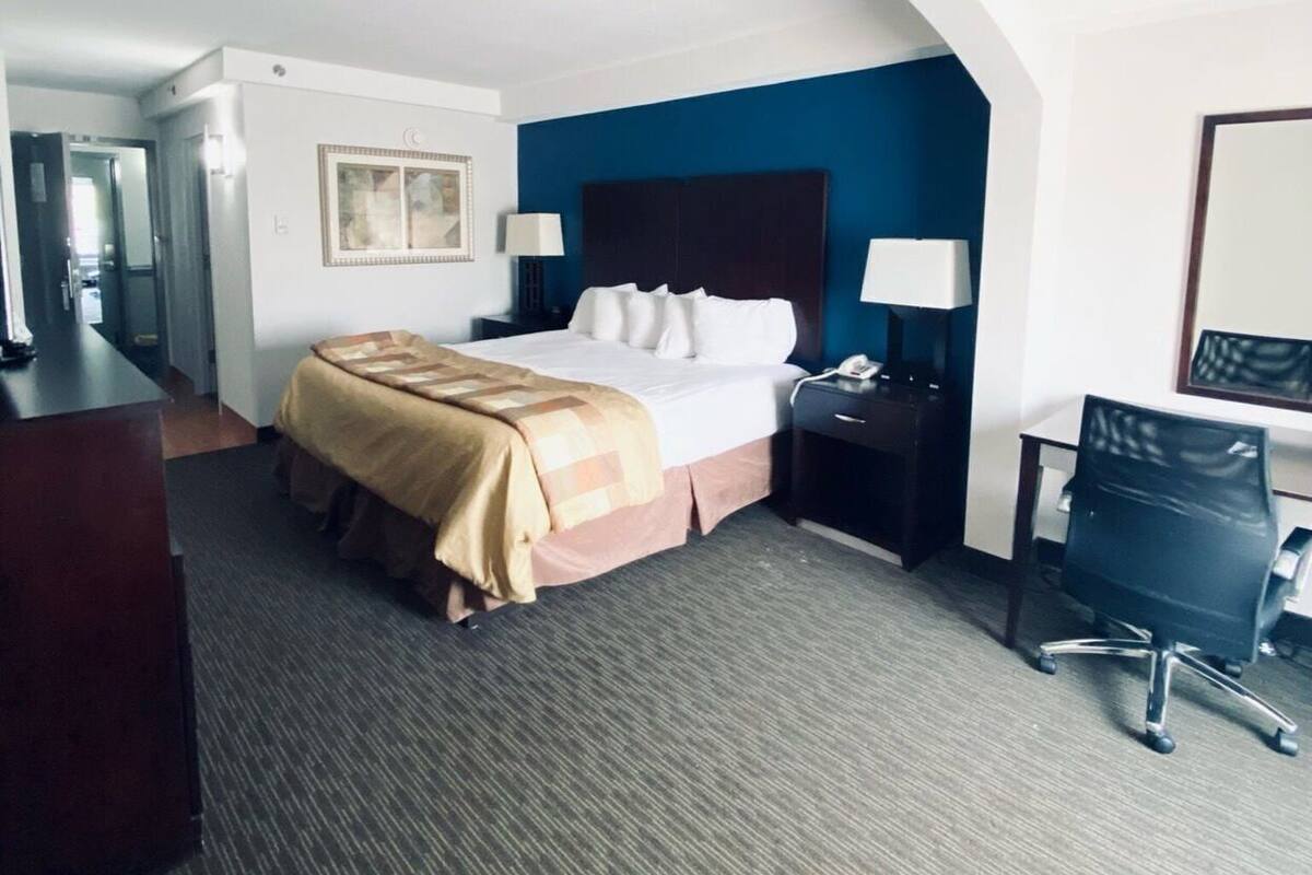 A hotel room with a bed, desk, chair, and a curved ceiling.