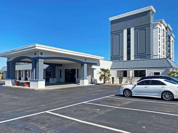 A modern building with a covered entrance and a parking lot.