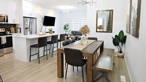 A modern kitchen with a central island, stainless steel appliances, and pendant lighting. - BoHo Modern Retreat w/King|Fireplace|Disney+ (Edmonton)