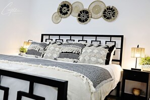 Ein ordentlich eingerichtetes Schlafzimmer mit einem Bett, Nachttischen und dekorativer Wandkunst.
