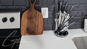 Una cocina con un microondas, una tabla de cortar de madera y un bloque de cuchillos.