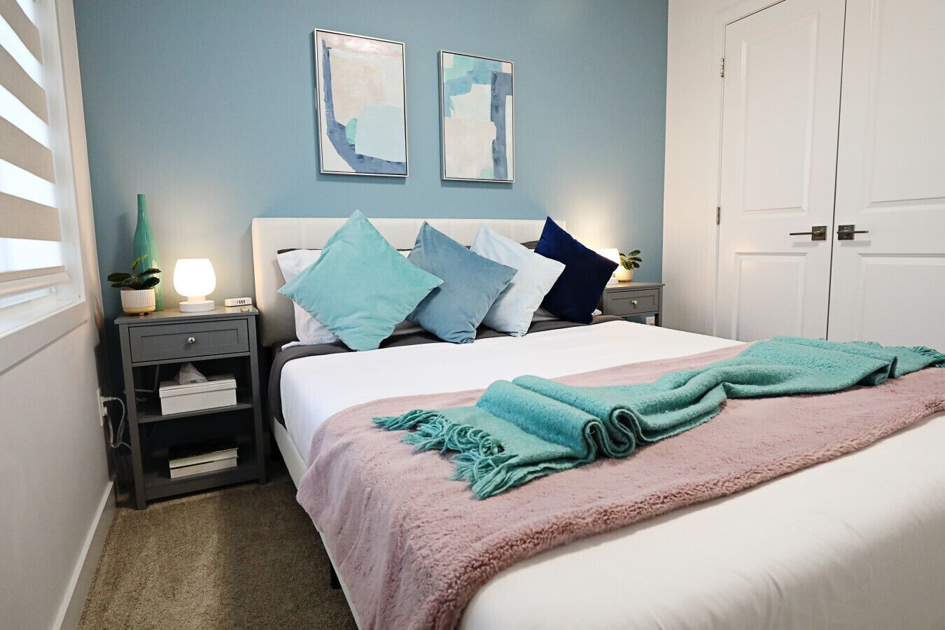 A bedroom with a bed, nightstands, a dresser, and two wall-mounted paintings.