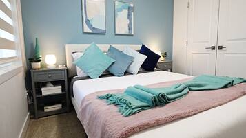 A bedroom with a bed, nightstands, a dresser, and two wall-mounted paintings.