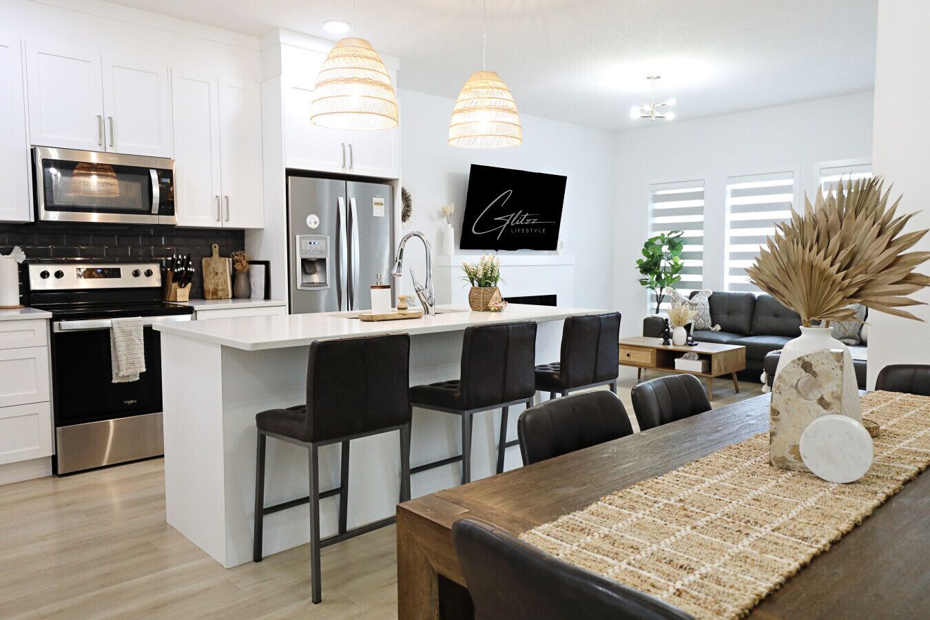 A modern kitchen with white cabinets, stainless steel appliances, and a central island with bar stools.