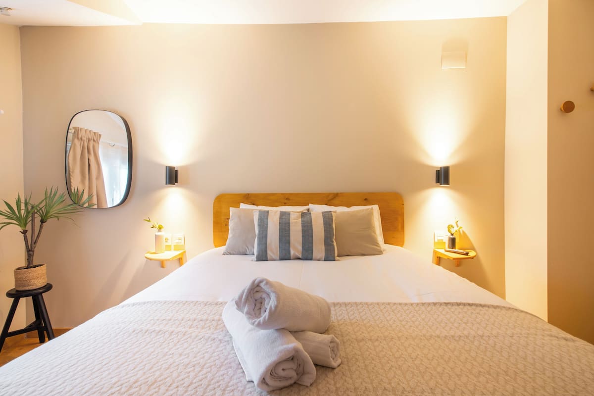 A neatly made bed with a wooden headboard, two bedside lamps, and a mirror on the wall.