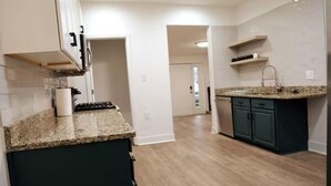 A modern kitchen with granite countertops, dark cabinetry, and a central island. - Spacious, Updated 4-bedroom Home near Short North Arts / Entertainment District (Columbus)