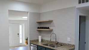 A modern kitchen with white subway tiles, a granite countertop, and a built-in dishwasher. - Spacious, Updated 4-bedroom Home near Short North Arts / Entertainment District (Columbus)