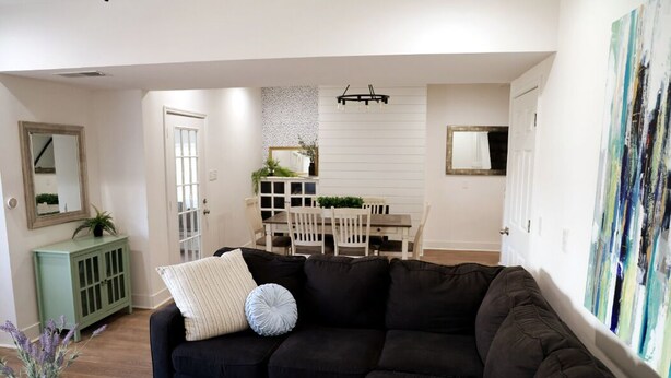 A living room with a black sectional sofa, a dining area with a white table and chairs, and a green cabinet. - Spacious, Updated 4-bedroom Home near Short North Arts / Entertainment District (Columbus)