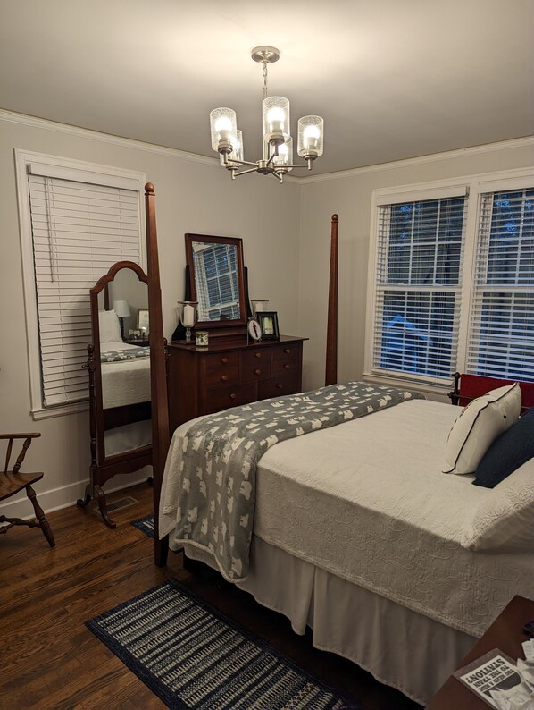 A bedroom with a four-poster bed, a wooden dresser, a mirror, and a chandelier. - Charming Country Cottage Near Augusta National (Augusta)