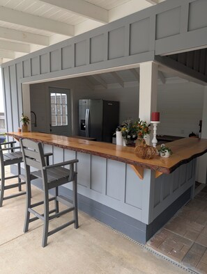 A kitchen with a wooden island, grey cabinetry, and a stainless steel refrigerator. - Charming Country Cottage Near Augusta National (Augusta)