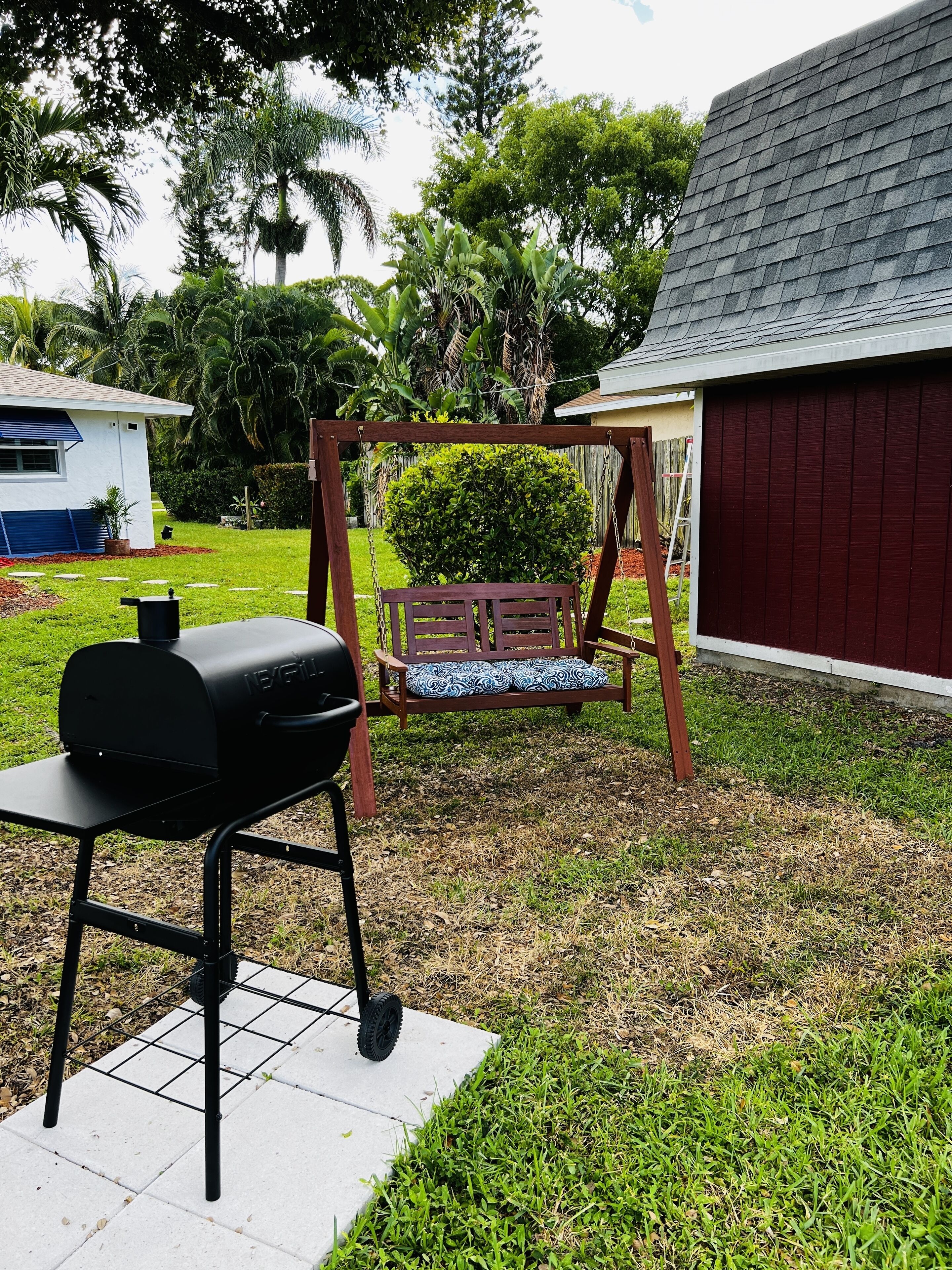A backyard with a barbecue grill, a swing set, and a shed.