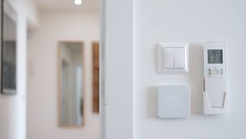 A thermostat and a light switch on a white wall.