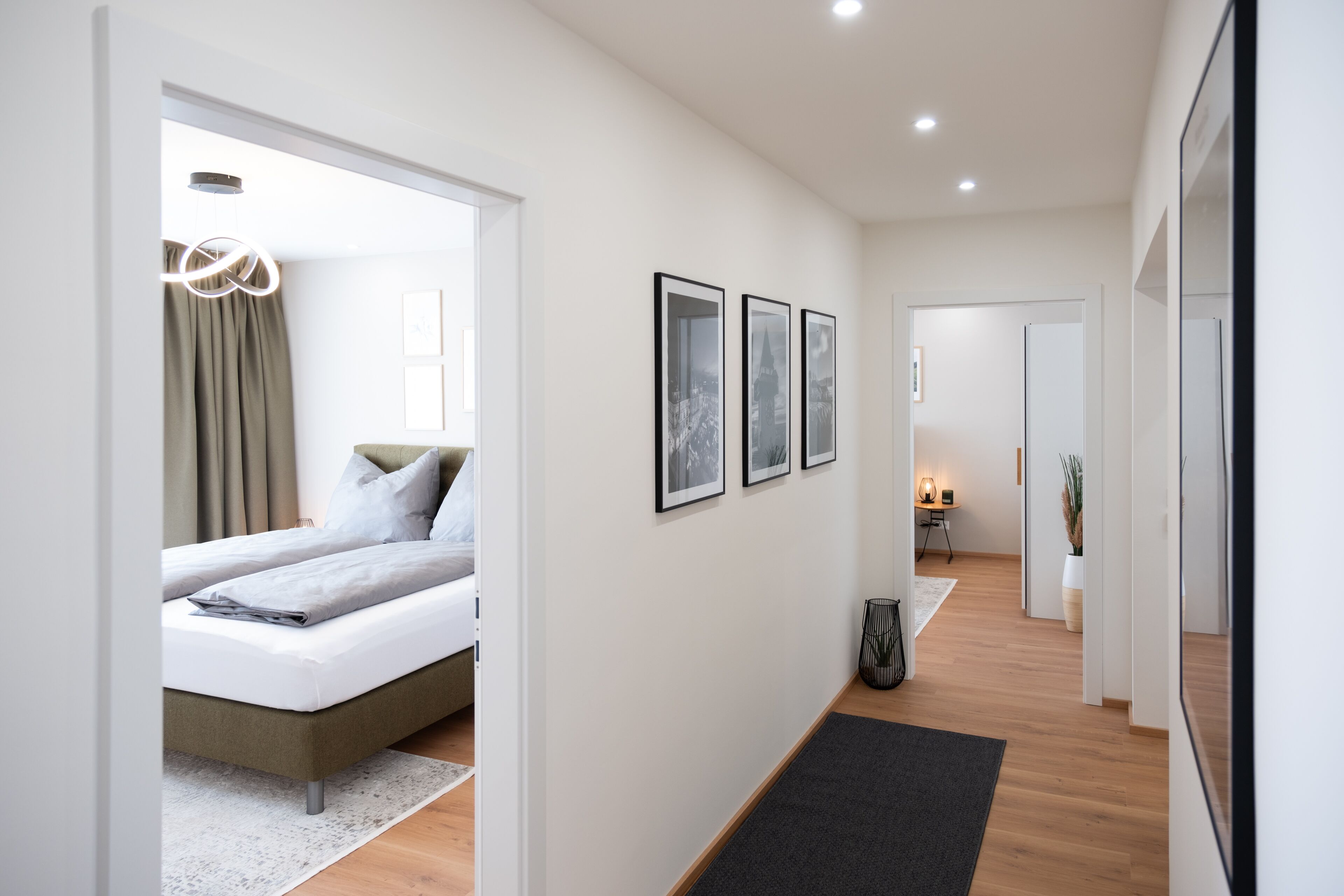 A modern hotel room with a bed, a bedside table, a lamp, and framed pictures on the wall.