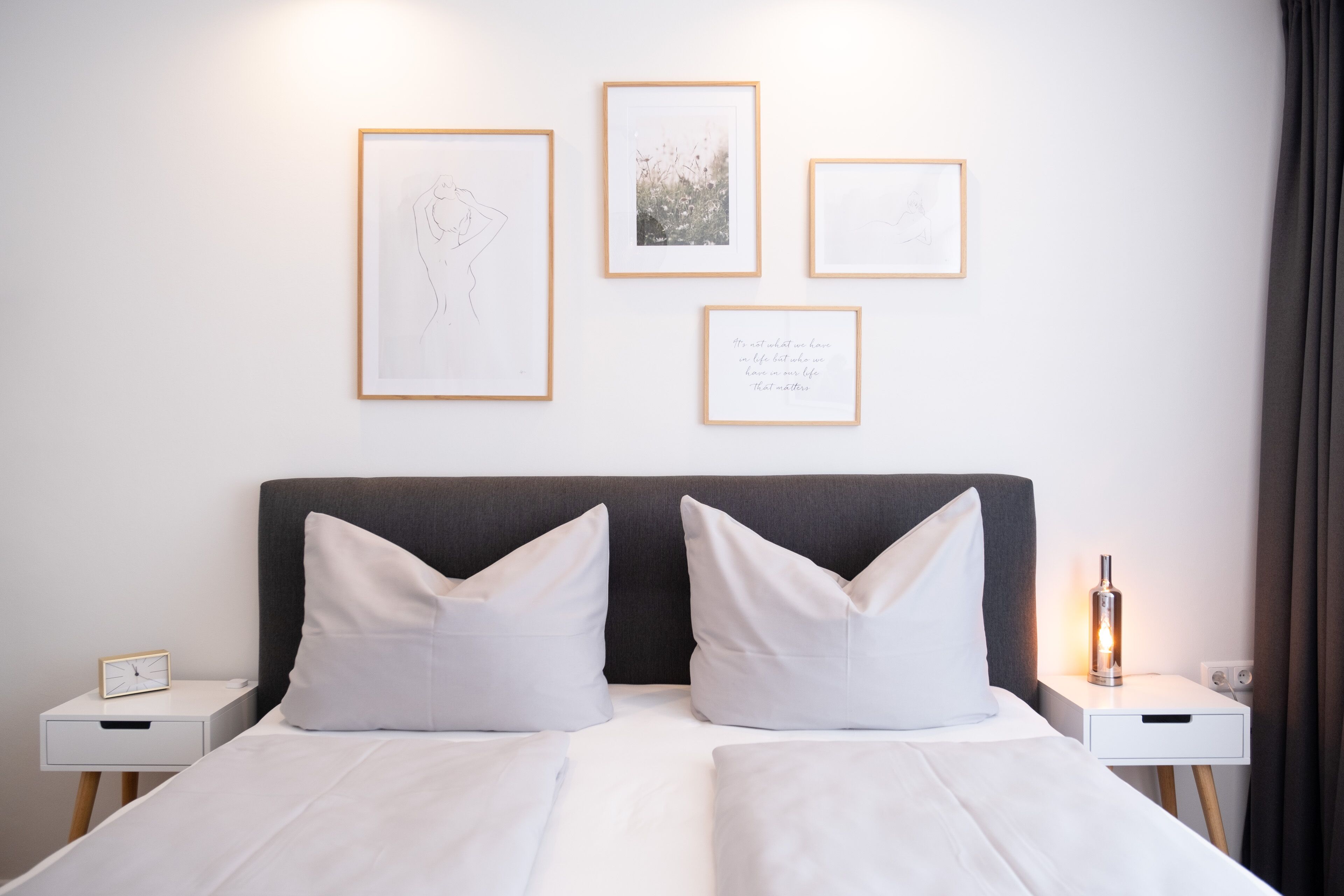 Una habitación de hotel con una cama, dos mesitas de noche y cuadros en la pared.
