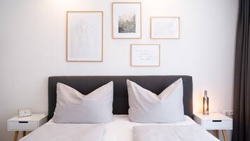Una habitación de hotel con una cama, dos mesitas de noche y cuadros en la pared.