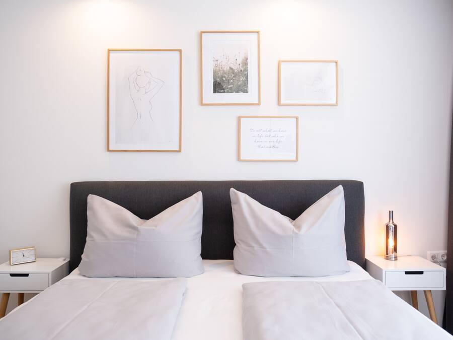 Una habitación de hotel con una cama, dos mesitas de noche y cuadros en la pared.
