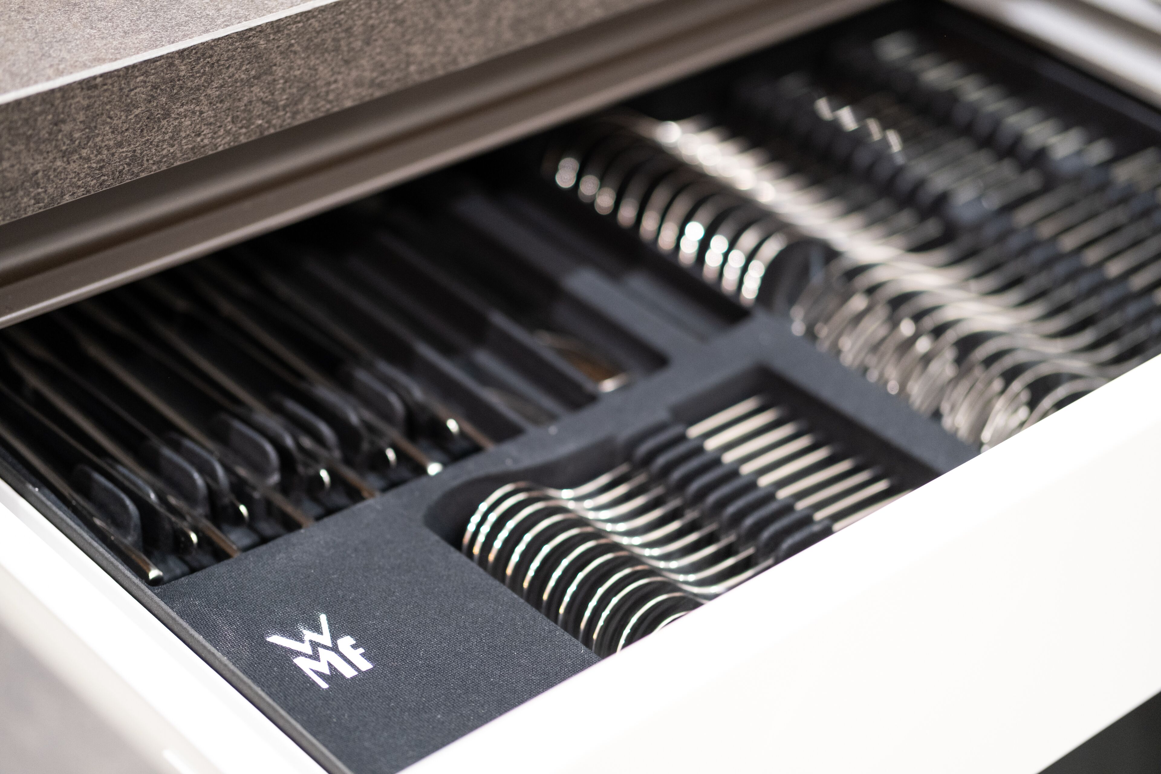 A close-up of a piano keyboard with a logo on the black felt.
