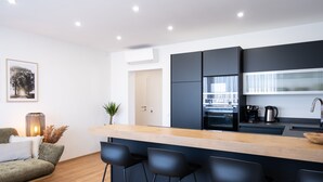 A modern kitchen with a wooden countertop, black bar stools, and a built-in oven.