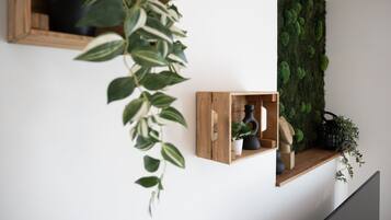 A modern interior with a wooden shelf holding a potted plant, a small wooden box, and a decorative item.